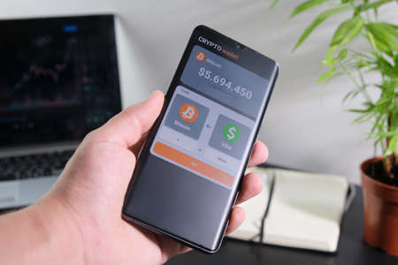 A man buys bitcoins in a mobile application. Smartphone with mobile application cryptocurrency wallet. The concept of cryptocurrency tradingの写真素材