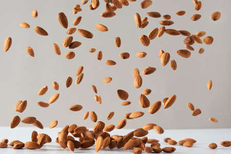 Flying almond nuts. Fresh raw almonds fall on a white background.Flying almond nuts. Fresh raw almonds fall on a white background.の写真素材