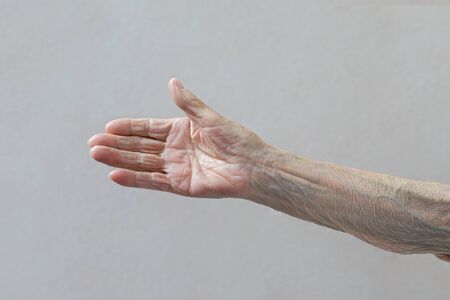 Old ladys hand. Elderly lady is waiting for help. Elderly concept with light background.の写真素材