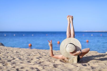 Young pretty hot sexy woman relaxing in swimsuit on stones with blue sea and sky on background. Summer Vacation Concept. Back View.の写真素材