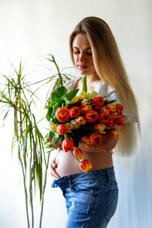 Fourth month of pregnancy. Beautiful pregnant woman with flowers. A series of photos of a pregnant...
