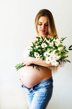Seventh month of pregnancy. Beautiful pregnant woman with flowers. A series of photos of a pregnant girl. Concept of pregnancy, motherhood, mother's dayの写真素材