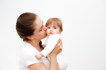 Bright portrait of happy mother holding infant child on hands. Mother hugging her little 6 months old baby. Childhood and baby care conceptの写真素材