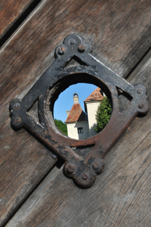 The view of the medieval buildings through the overview window of the old wooden gate. Selective focusの写真素材
