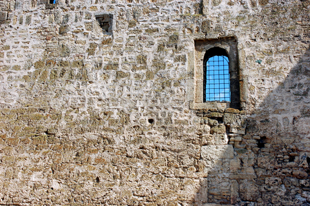 Old stone wall built of  limestone bricks with a small window with bars. Masonry bricks background. Stone texture for scrapbooking, decoupageの写真素材