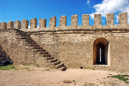 Fragment of the fortress wall with stairs and embrasure. Background of stone  wall texture photoの写真素材
