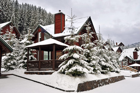 Wooden cottage holiday house in mountain holiday resort covered with fresh snow in winter.