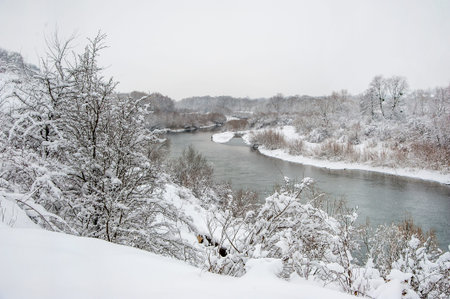 Winter landscape with the river during snowfall