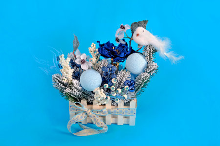 Beautiful handmade Christmas tree composition with a bird and festive decor on a blue background.の写真素材