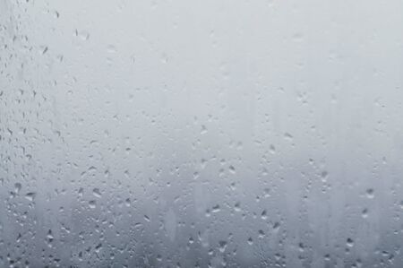 Drops water on window. Spotted abstract texture background. Spring wet weather. Droplets on glass. Fit to autumn.の写真素材