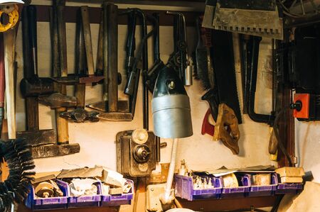 Workshop scene. Old tools hanging on wall in workshop. Vintage retro garage style. Old wrenches hanging wall in old garage. Garage tools.の写真素材