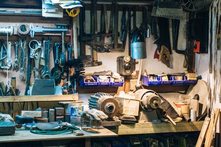 Workshop scene. Old tools hanging on wall in workshop. Vintage retro garage style. Old wrenches hanging wall in old garage. Garage tools.の写真素材
