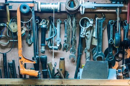 Workshop scene. Old tools hanging on wall in workshop. Vintage retro garage style. Old wrenches hanging wall in old garage. Garage tools.の写真素材