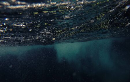 Underwater shot of blue ocean water, air bubbles, sunbeams on water surfaceの写真素材