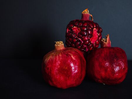 red pomegranate whole and cut on a dark black backgroundの写真素材