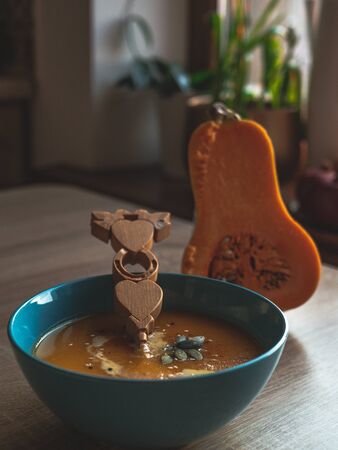 Creamy pumpkin soup topped with pumpkin seeds and cream in a blue bowl close up.の写真素材