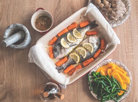 Raw dorado fish with spices lemon and vegetables, cooking on baking tray.の写真素材