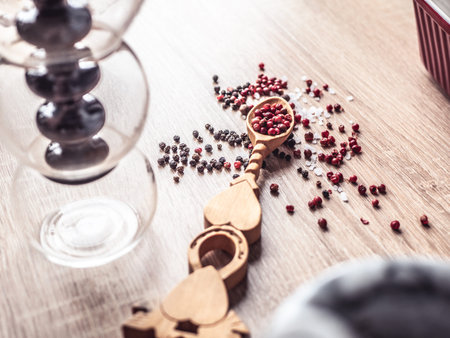 Black and red pepper on a vintage spoon. Variety of spices on wooden kitchen table. Top view.の写真素材