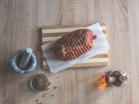 Baking tray with raw meatloaf on table. Cooked spicy pork meat roulade prepared to roast, marinated with spices and herbs on black slate plate, close-upの写真素材