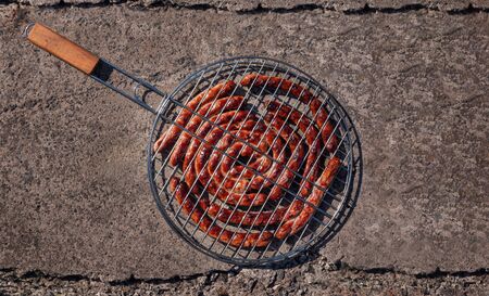 Grilling basket with roasted Bavarian sausages on concrete background. BBQ outside.の写真素材