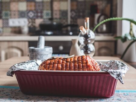 Baking tray with raw meatloaf on table. Cooked spicy pork meat roulade prepared to roast, marinated with spices and herbs on black slate plate, close-upの写真素材