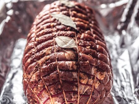 Baking tray with raw meatloaf on table. Cooked spicy pork meat roulade prepared to roast, marinated with spices and herbs on black slate plate, close-upの写真素材