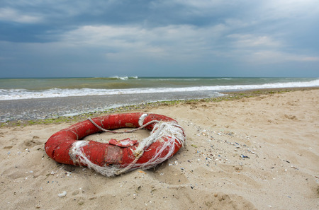 Old damaged lifebuoy on sandの写真素材