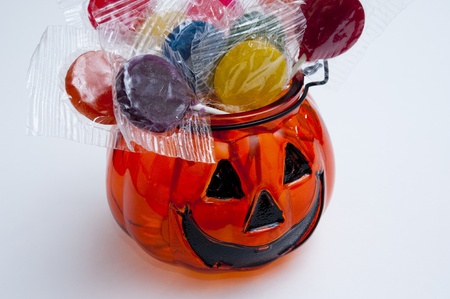 Glass Jack-o-lantern filled with lollipops of assorted colorsの写真素材