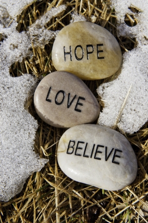 Hope, Love and believe rocks in the melting spring snowの写真素材