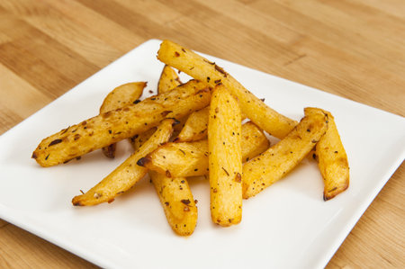 White plate of rutabaga fries on wood