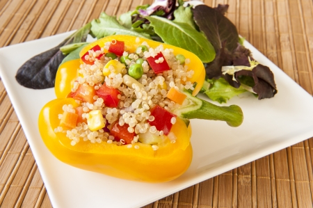 Yellow pepper stuffed with quinoa and mixed vegetables with green saladの写真素材
