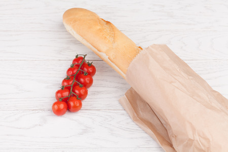 Fresh cherry tomatoes on branch and  baguette  on a wooden tableの写真素材