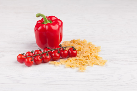 Tomatoes, red pepper and macaroni on white tableの写真素材