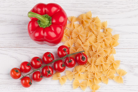 Tomatoes, red pepper and macaroni on white tableの写真素材