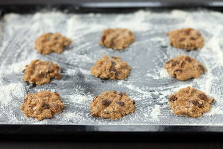 uncooked oatmeal cookies with raisins on baking trayの写真素材
