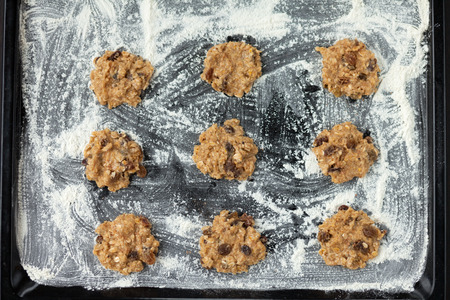 uncooked oatmeal cookies with raisins on baking trayの写真素材