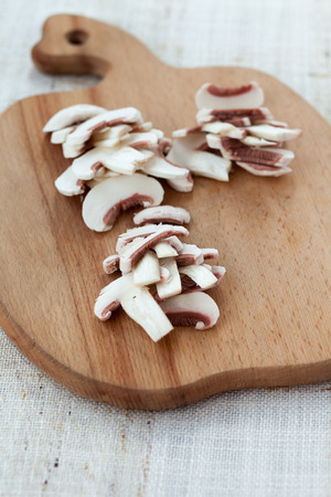 Sliced fresh white button mushrooms on a wooden chopping boardの写真素材