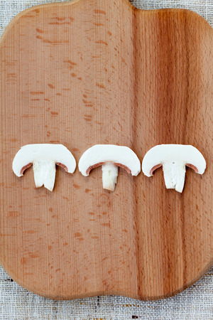 Sliced fresh white button mushrooms on a wooden chopping boardの写真素材