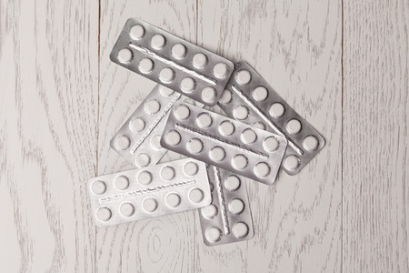 White and yellow pills in blister pack on wooden tableの写真素材