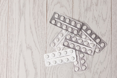 White and yellow pills in blister pack on wooden tableの写真素材