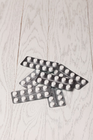 White and yellow pills in blister pack on wooden tableの写真素材