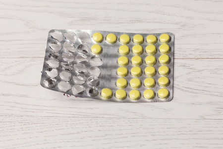 Yellow pills in blister pack on wooden tableの写真素材