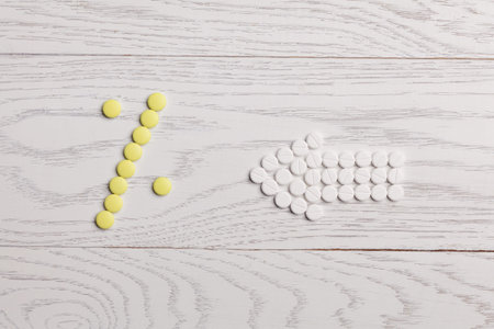 Arrow of white pills point to percent of yellow pills on wooden table