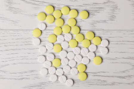 White and yellow pills on wooden tableの写真素材