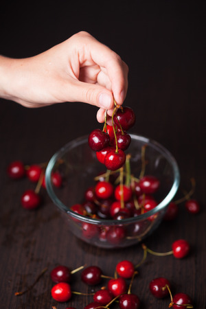 Fresh cherries in woman hands on wooden tableの写真素材