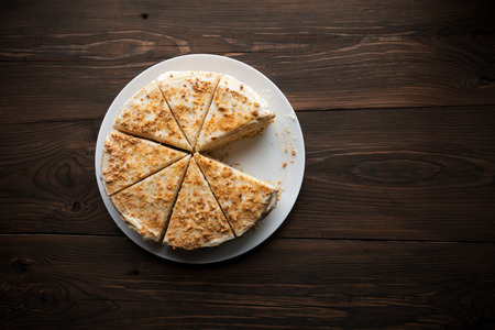 Homemade honey cake with cut piece on a wooden tableの写真素材
