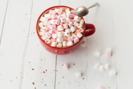 Hot chocolate with marshmallows in red cup on wood table