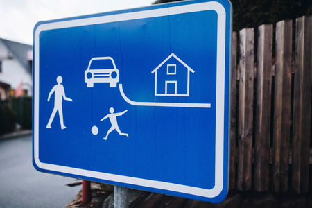 Blue street sign with kids, house and car on it outdoorの写真素材