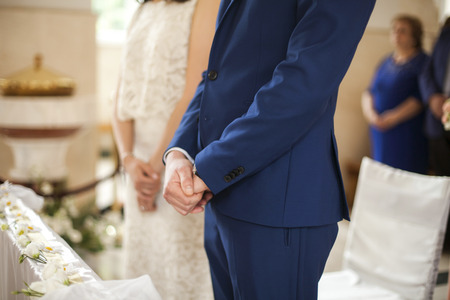 Closeup image of bridegrooms hands on marriage ceremony inside church blur backgroundの写真素材