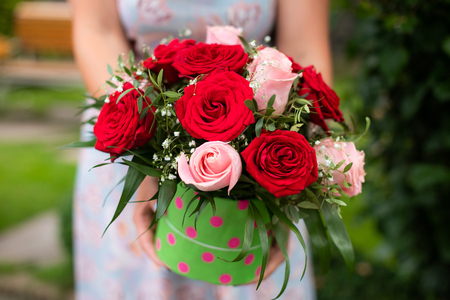 Woman hands hold box with flower bouquet of red and pink roses outdoor nature backgroundの写真素材